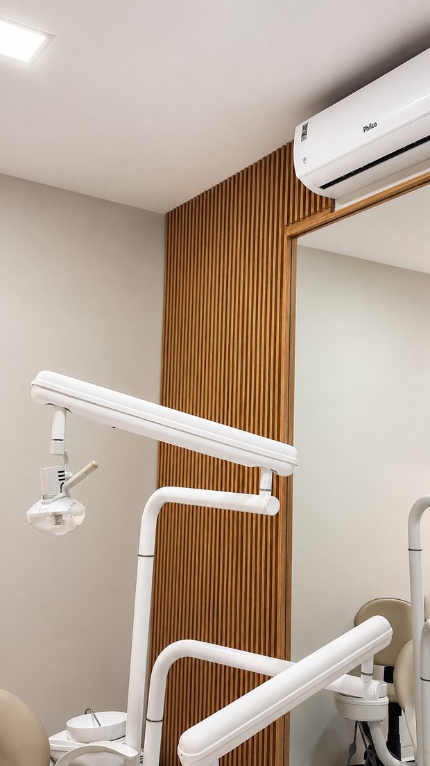 Consultório da Clínica ALOL com painel ripado de madeira e refletor odontológico